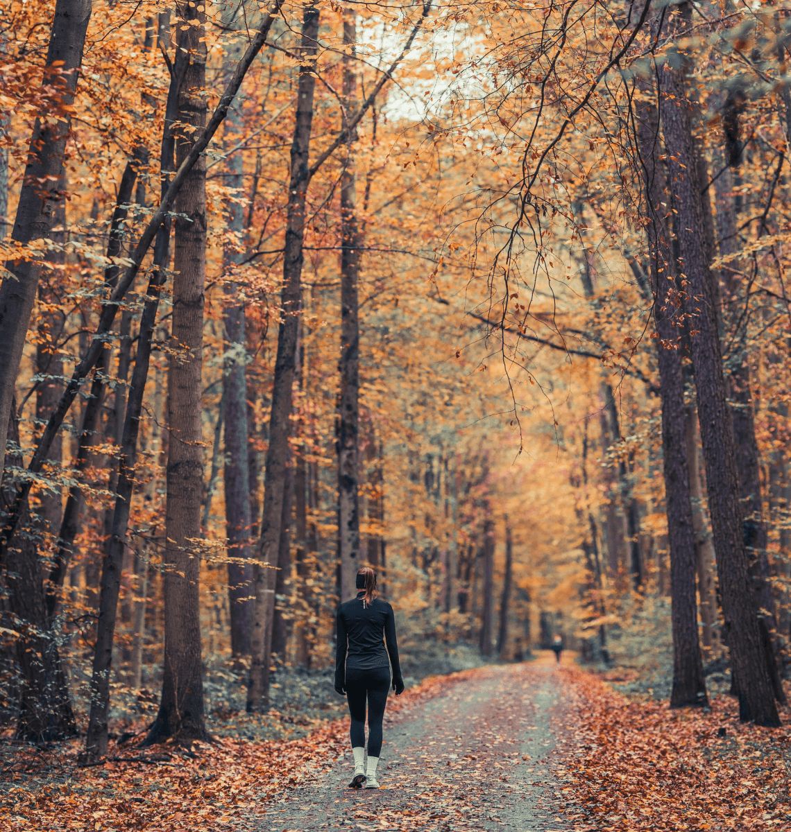 A woman enjoying a reflective moment while walking through a serene autumn forest.